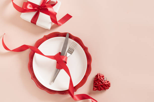 istock Valentines day table place setting with red rose, two hearts on pink background. 2197964914