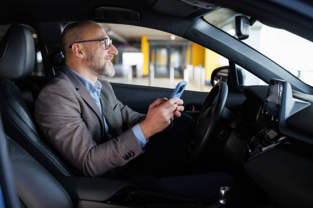 istock Man sitting on a driver's seat and using a smart phone 2197965930