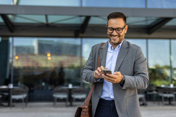 istock Businessman in a suit using phone in front of an office building 2197971385