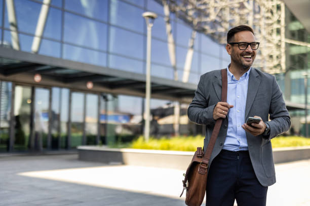 istock Businessman in a suit using phone in front of an office building 2197971418