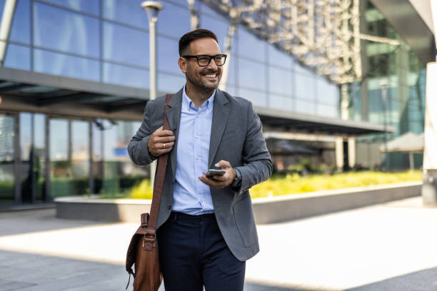 istock Businessman in a suit using phone in front of an office building 2197971422