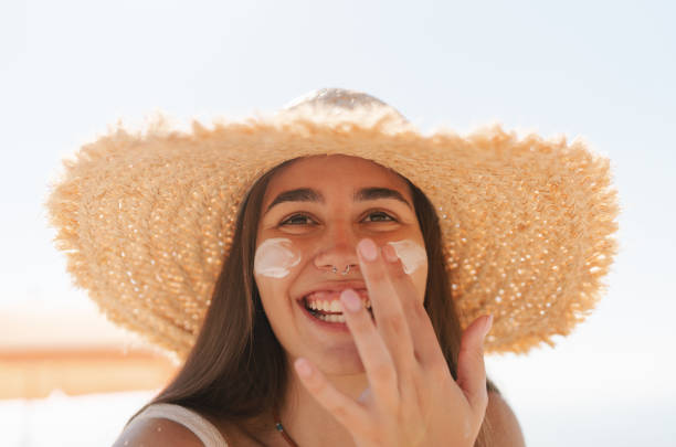 istock Young woman applying sunscreen on her face while at the beach 2197971624