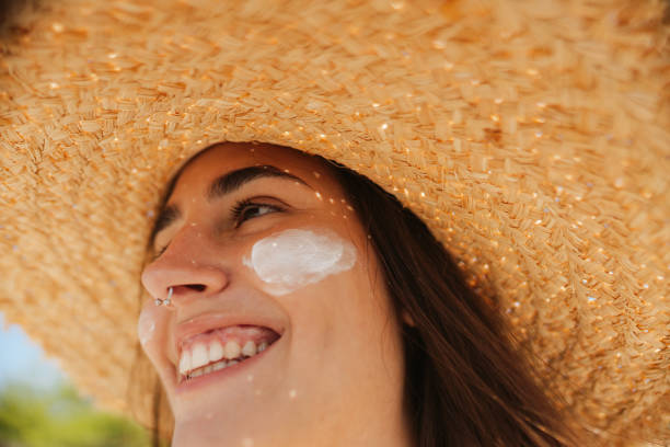 istock Young woman applying sunscreen on her face while at the beach 2197971661