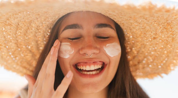 istock Young woman applying sunscreen on her face while at the beach 2197971665