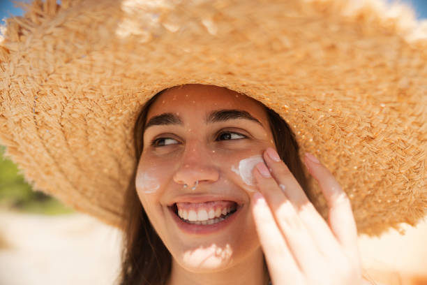 istock Young woman applying sunscreen on her face while at the beach 2197971688