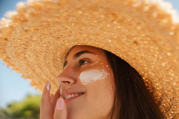 istock Young woman applying sunscreen on her face while at the beach 2197971747