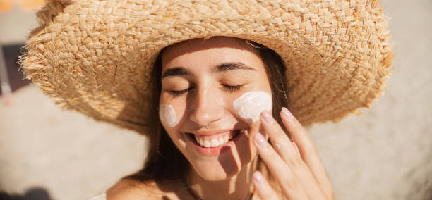 istock Young woman applying sunscreen on her face while at the beach 2197971754