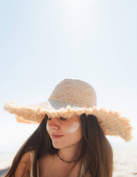 istock Young woman applying sunscreen on her face while at the beach 2197971756