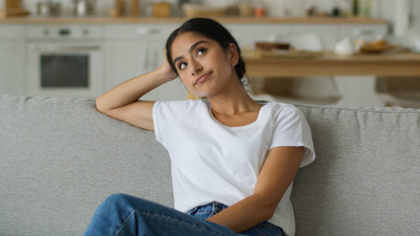 istock Close up boring sad upset frustrated thinking suffer disappointed bored think pensive thoughtful Hindu woman Indian girl Arabian female lady at home couch problem at sofa confused puzzled hesitate 2197972508