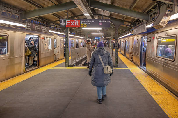 New York Subway, Queensboro Plaza Station, Queens, New York, United States - January 14th 2025:  Woman in winter clothes walking toward an Exit sign at the elevated subway station