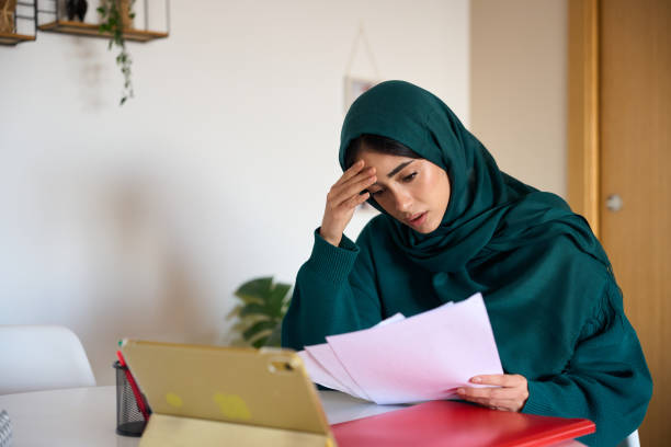 istock Young woman analyzing financial documents at home 2197977483