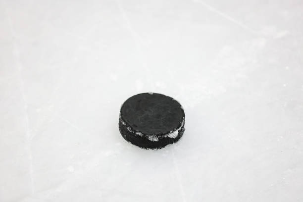 istock Small Black Ice Hockey puck laying on skated ice. 2197977778