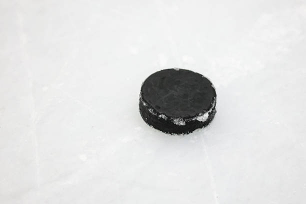 istock Small Black Ice Hockey puck laying on skated ice. 2197977785
