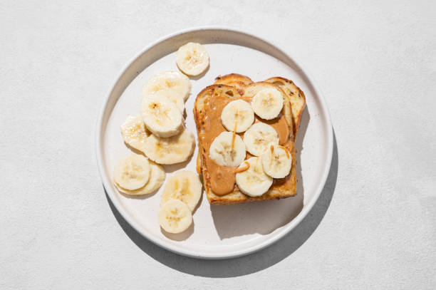 istock Peanut butter toast on a plate with banana on a light background with  shadow. 2197983437