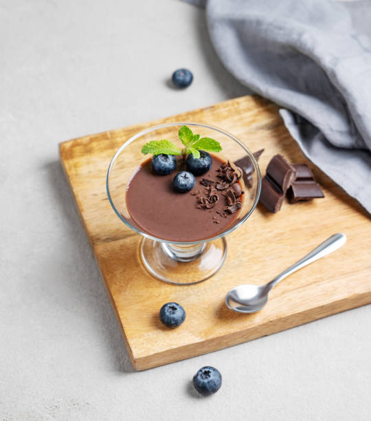 istock Chocolate pudding in a glass with fresh blueberries and mint on a wooden board on a light background 2197983439