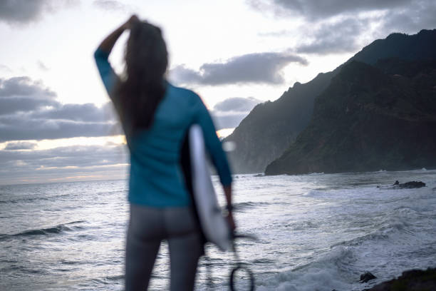 istock Surfer In Wetsuit With Surfboard at Dawn Watching The Waves 2197983976