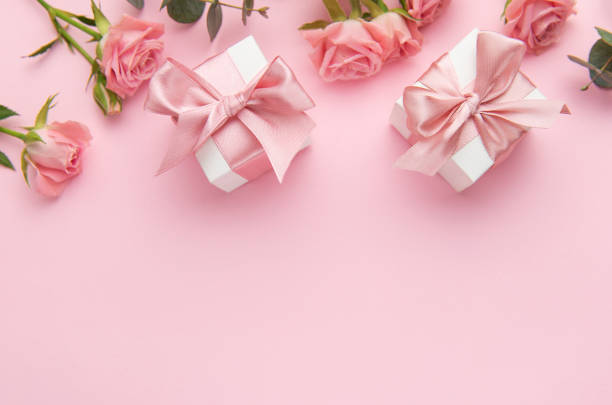 istock Pink roses and gift boxes with satin ribbons lying on pink background 2197986685