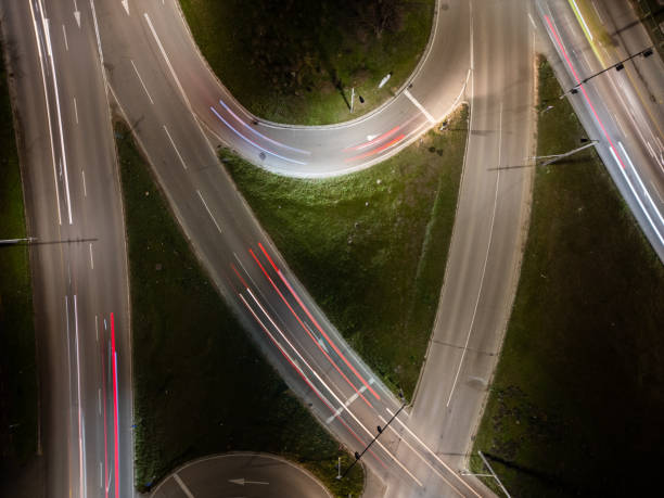 istock Top down aerial view of a night intersection with a moving traffic. Vehicles create dynamic light trails, showcasing urban speed, motion, and modern transportation infrastructure 2197986835