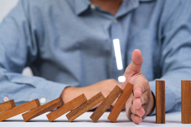 istock A person stops falling wooden blocks, symbolizing prevention and control in decision-making. Focus on strategy and balance. 2197987208