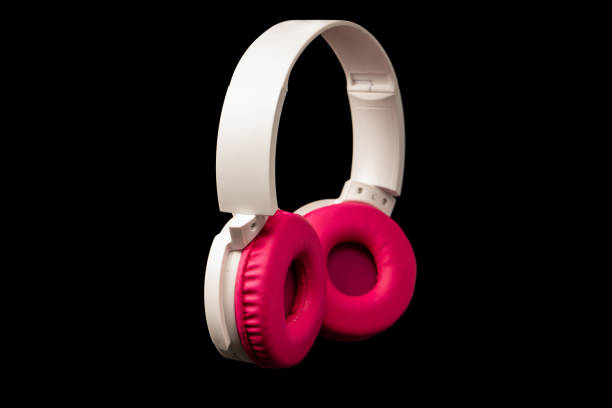 Pink and white headphones isolated on a black background.
