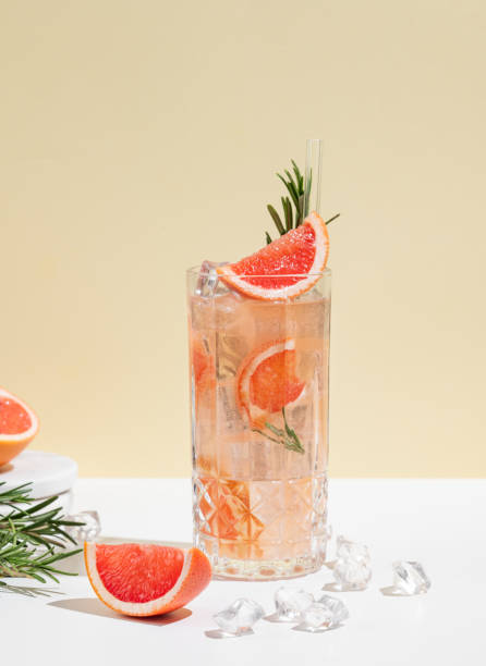 istock Refreshing cocktail with grapefruit, rosemary and ice in a glass on a white yellow background with shadow. 2197987447