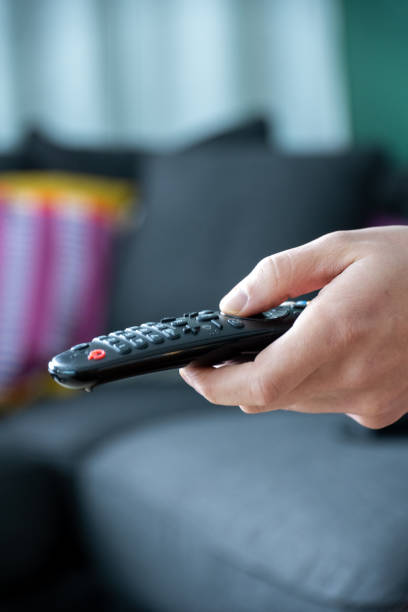 istock close up of television remote control in casual man hands 2197989576