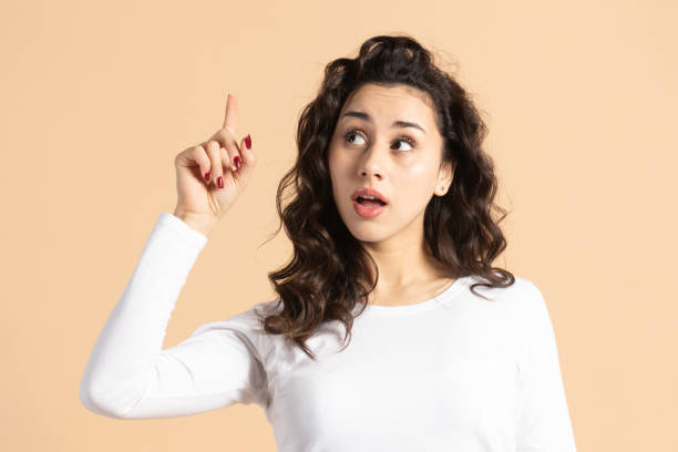istock Woman pointing one finger up and looking aside the camera 2197990223