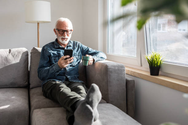 Smiling mature man using smartphone at home