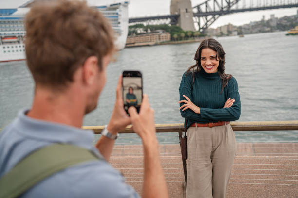 istock Young adults enjoying a sunny day by Sydney Harbor while capturing joyful moments with a smartphone 2197995794