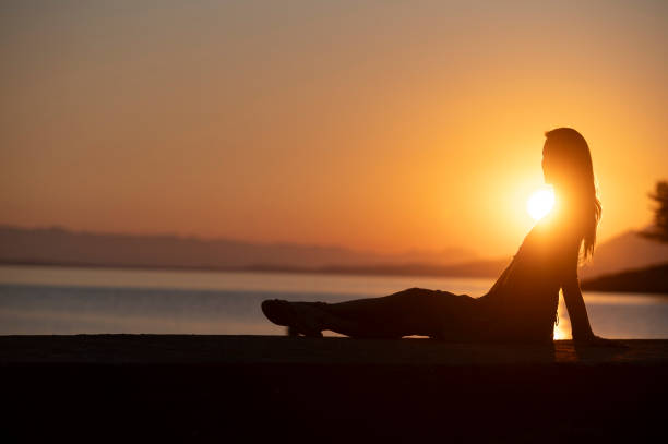 istock Woman relaxing at sunset by the water 2197998524