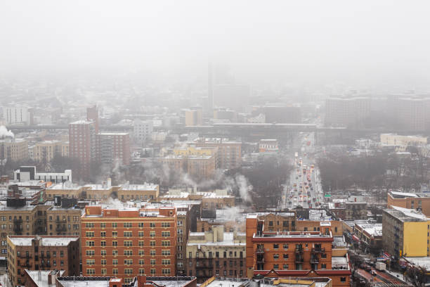 High angle view of snow falling in the Norwood neighborhood of the Bronx, New York City. Winter storm in the city, aerial view of apartment buildings and morning traffic.