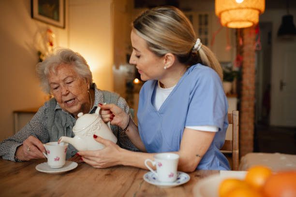 istock Lovely eldery woman serving tea to friendly caregiver. 2197999945
