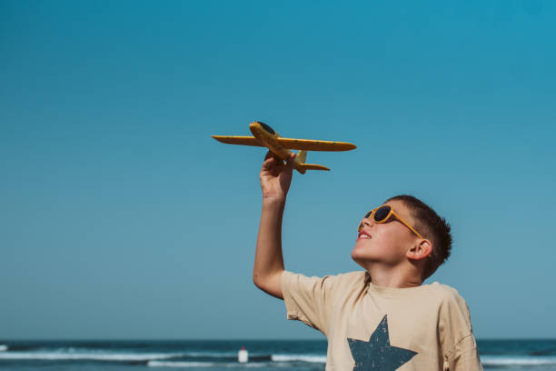 istock Boy playing on a sandy beach with foam airplane. 2198000371