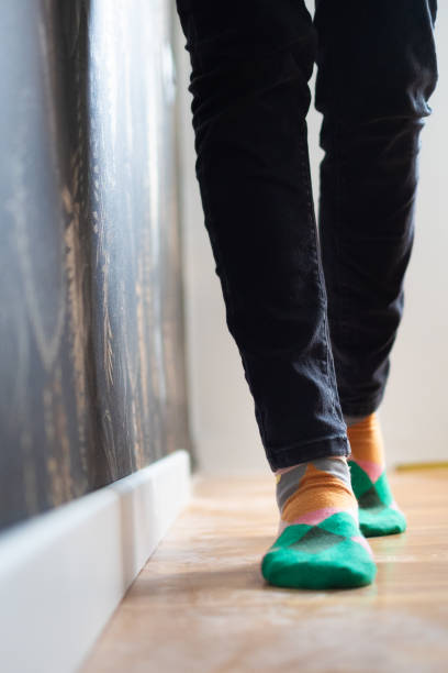 istock Painter wearing colorful socks stands next to a freshly painted wall 2198004006