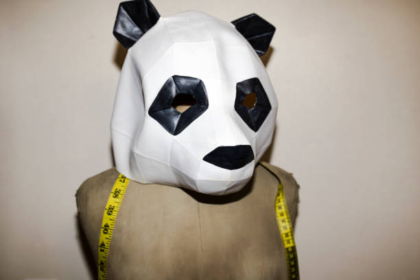 istock Person wearing geometric panda mask with measuring tape 2198004405