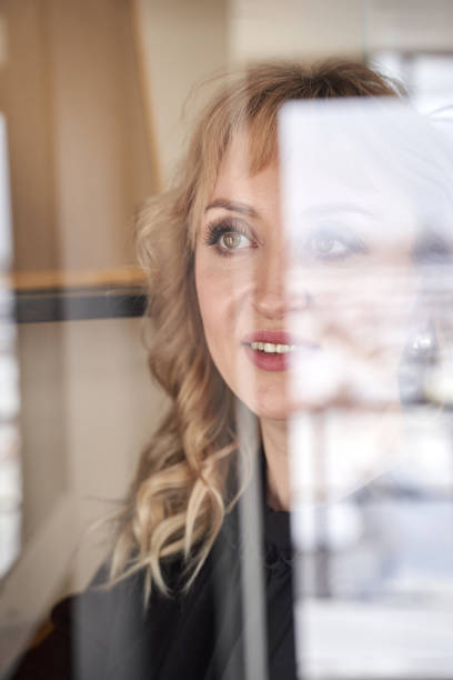 istock Reflective woman smiling through glass window in soft natural light 2198004542