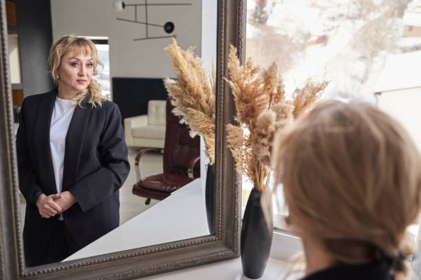 istock Woman in black blazer reflecting in mirror with modern interior and pampas grass 2198004554