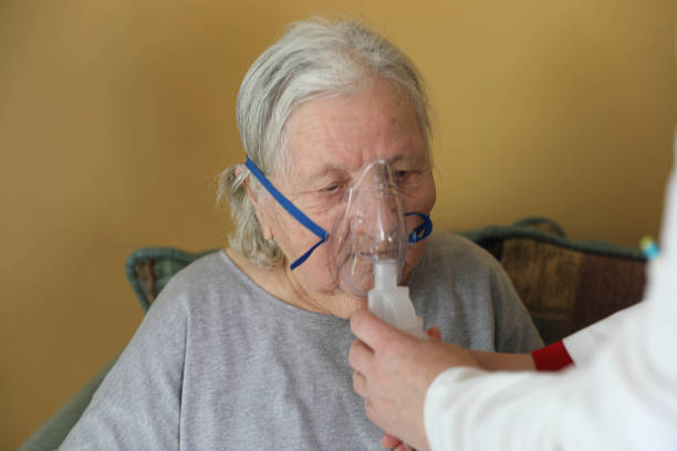 istock Senior woman doing inhalation through oxygen mask at home 2198004862