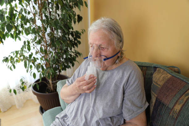 istock Senior woman doing inhalation through oxygen mask at home 2198004873