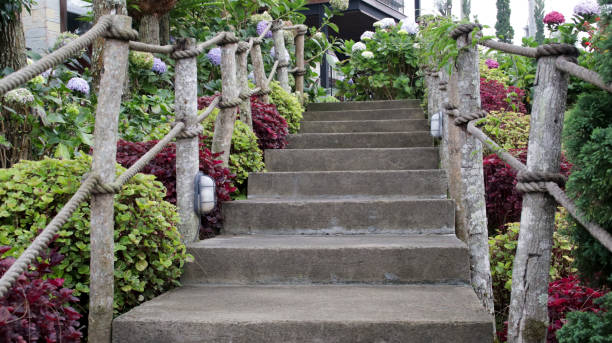 istock Rustic Stone Staircase with Wooden Rope Handrails Surrounded by Vibrant Hydrangeas and Lush Greenery Leading to a Wooden House in a Scenic Garden 2198004897
