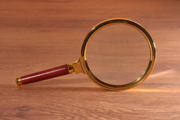 Golden Magnifying glass, standing on a wooden background