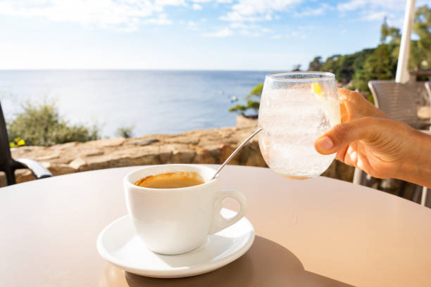 Relaxing with a cup of coffee and a glass of sparkling water on a table, enjoying a scenic coastal view filled with tranquility in the Mediterranean Sea, Spain.