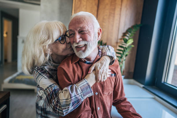 istock An elderly couple is embracing in the kitchen, their arms wrapped around each other in a warm and loving hug. Both have gray hair, a symbol of the years they have shared together. 2198006537