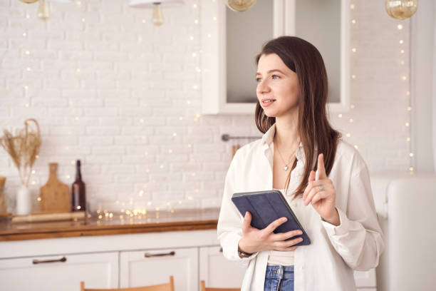 istock Woman holding tablet in bright kitchen with fairy lights and modern decor 2198007403
