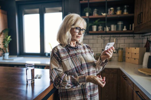 istock An elderly woman is holding a few tablets in her hand, looking at them thoughtfully. Her fingers gently cradle the pills as she considers them. 2198007409