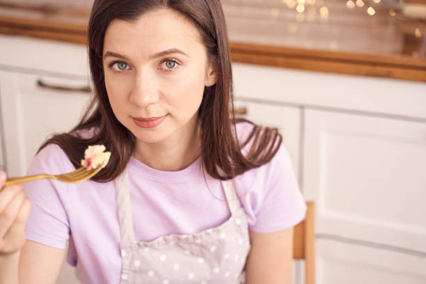 istock Woman in kitchen holding fork with dessert while wearing a pastel apron, express 2198007429