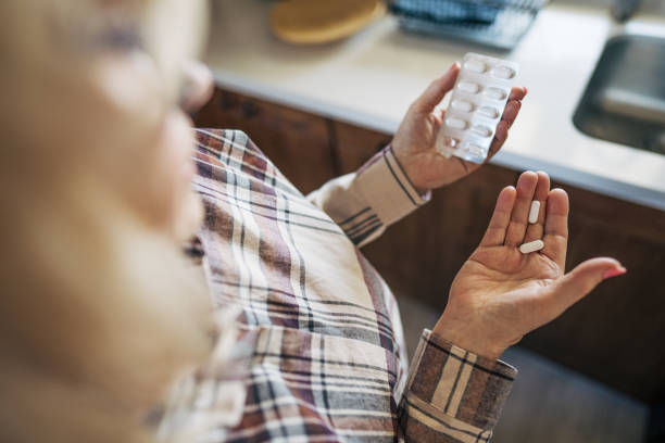 istock An elderly woman is holding a few tablets in her hand, looking at them thoughtfully. Her fingers gently cradle the pills as she considers them. 2198007540
