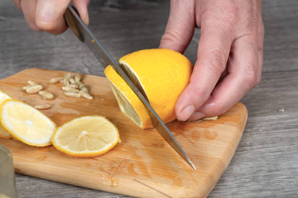 istock woman's hands cut lemon with a knife on a cutting board. Preparing for canning. 2198007763