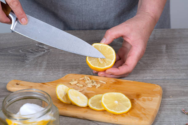 istock woman's hand cuts and peels a lemon with a knife. Preparing for conservation. Close-up. 2198007797