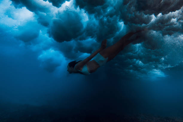 istock Woman in bikini dive without surfboard under ocean wave. Duck dive under crashing wave 2198007803